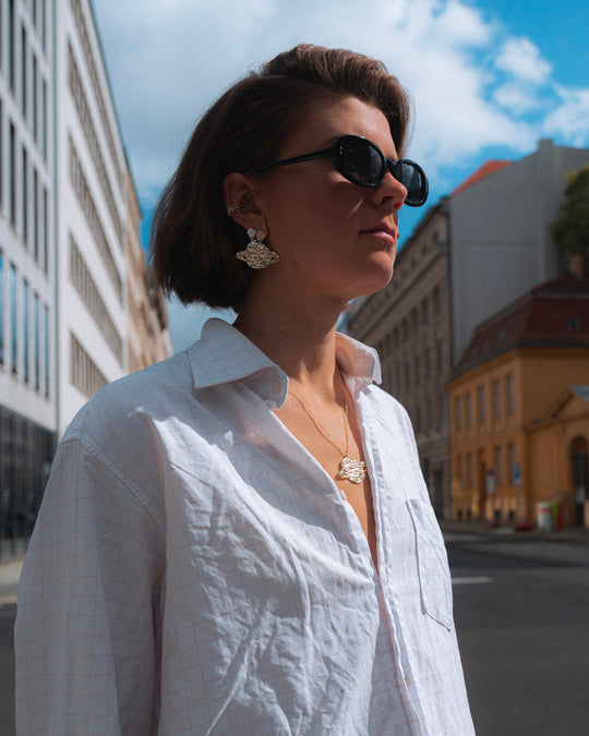 Saturn Necklace Gold worn with the Saturn earrings and a white shirt